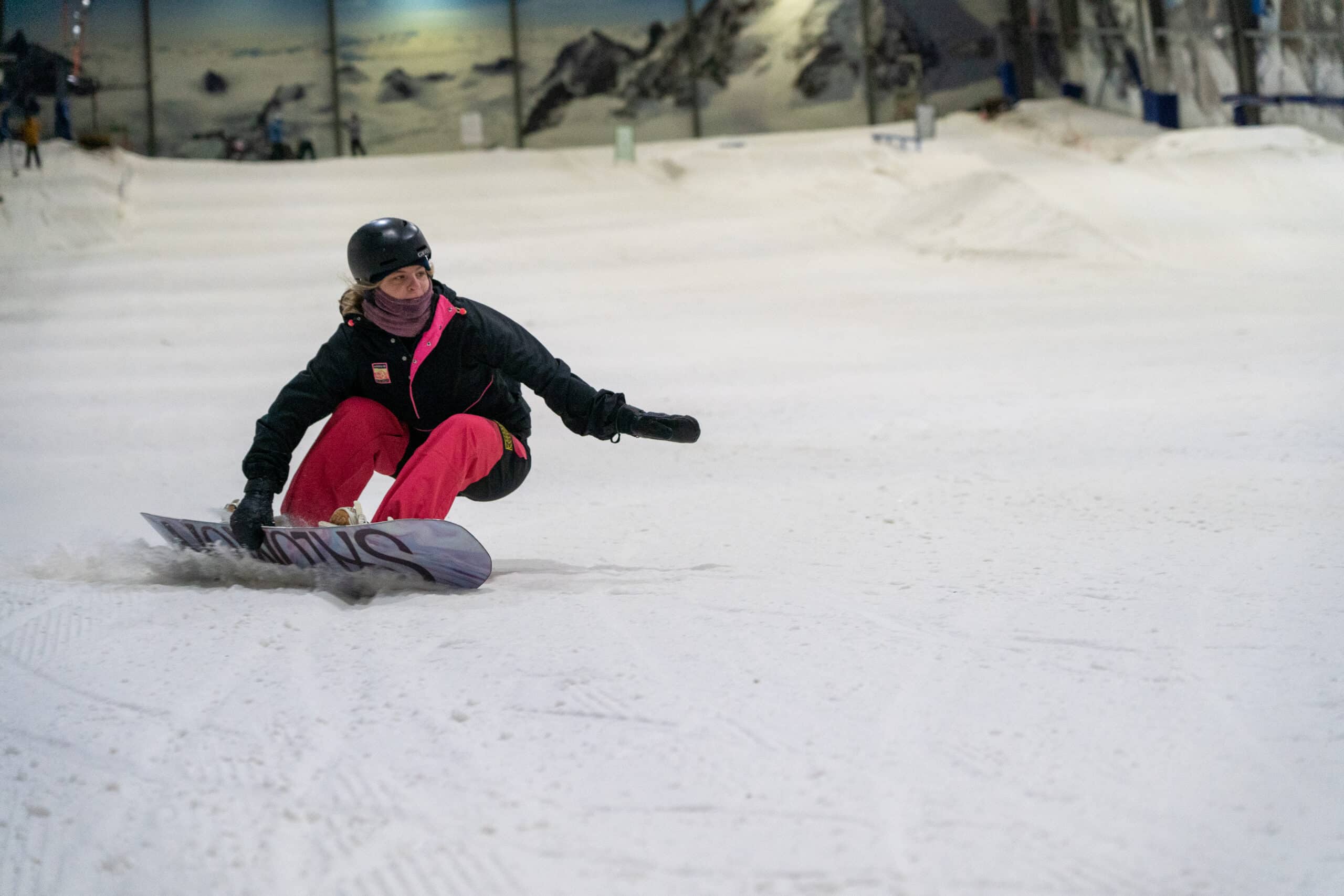 Snowboard makes a deep turn at Snowplanet indoor ski resort