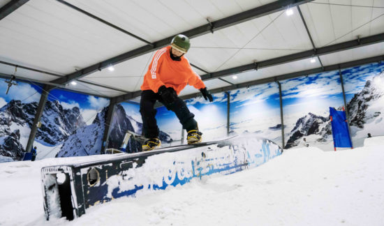 Snowboarder riding terrain park at night in Auckland's Snowplanet