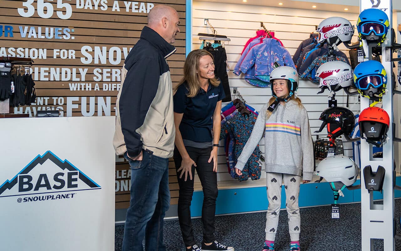 Cute girl tries on a helmet in the Base Retail Ski Shop at Snowplanet