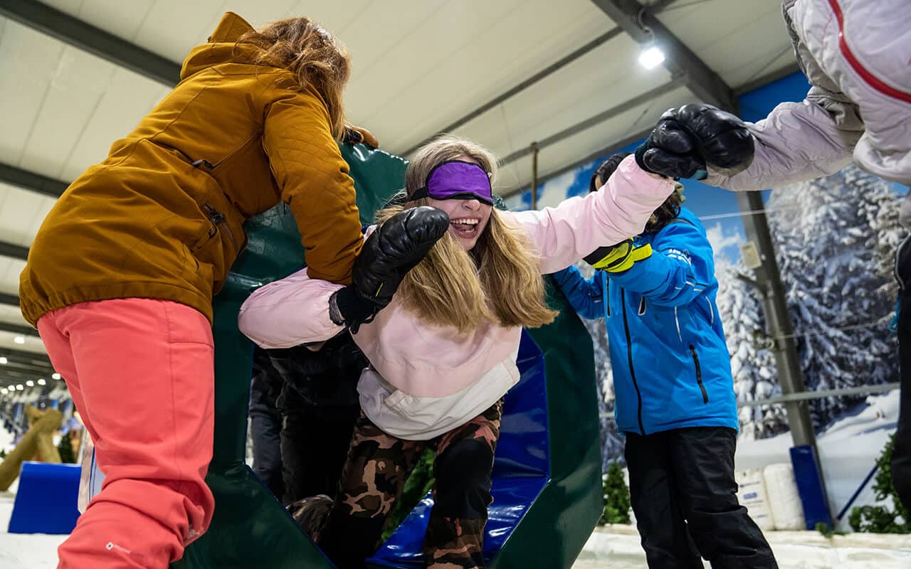 Woman blindfolded in the snow during team building event at Snowplanet.