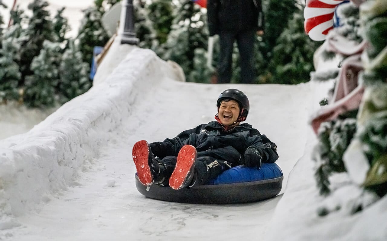 Man snow tubing at a team building event in Snowplanet