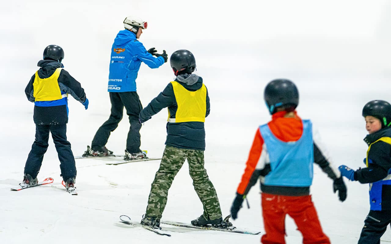 Kids follow an instructor down the ski slope in Snowplanets after school program
