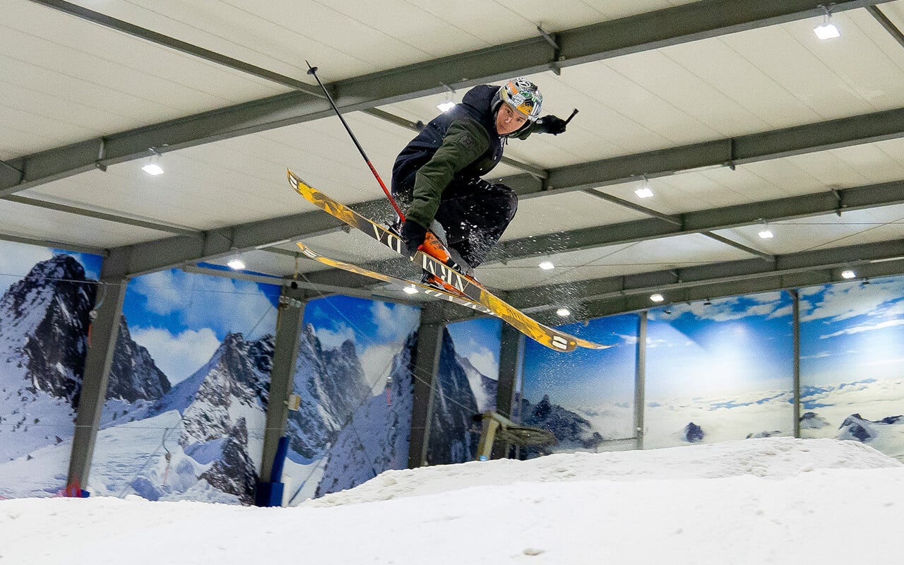 Man does a jump on skis in the terrain park at Snowplanet